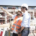 Kask ve yelek giyen iki inşaat çalışanı, Sakarya'da şantiye güvenliği üzerine konuşuyor